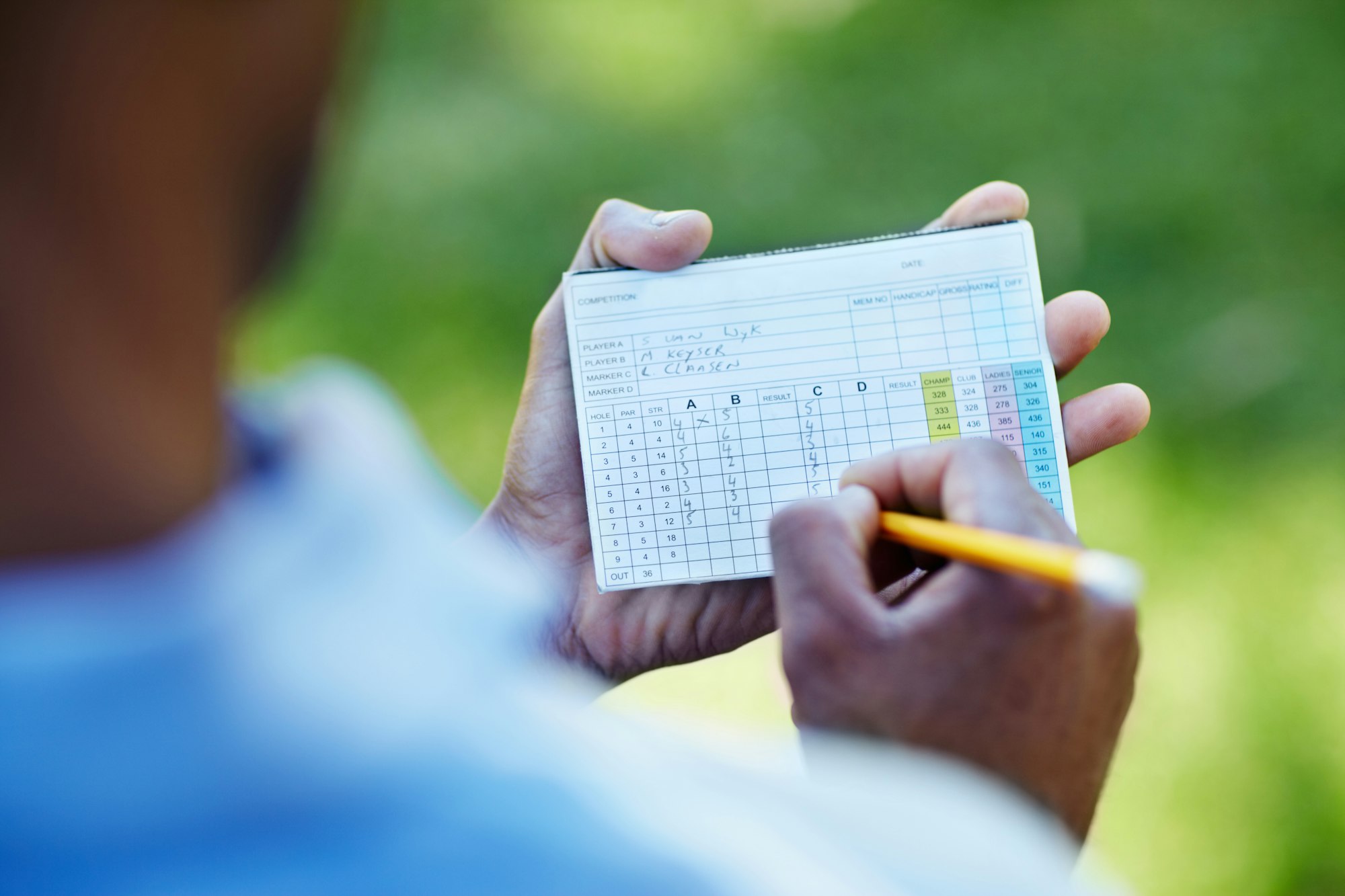 Staying below par. Rearview shot of a young golfer marking his scorecard.