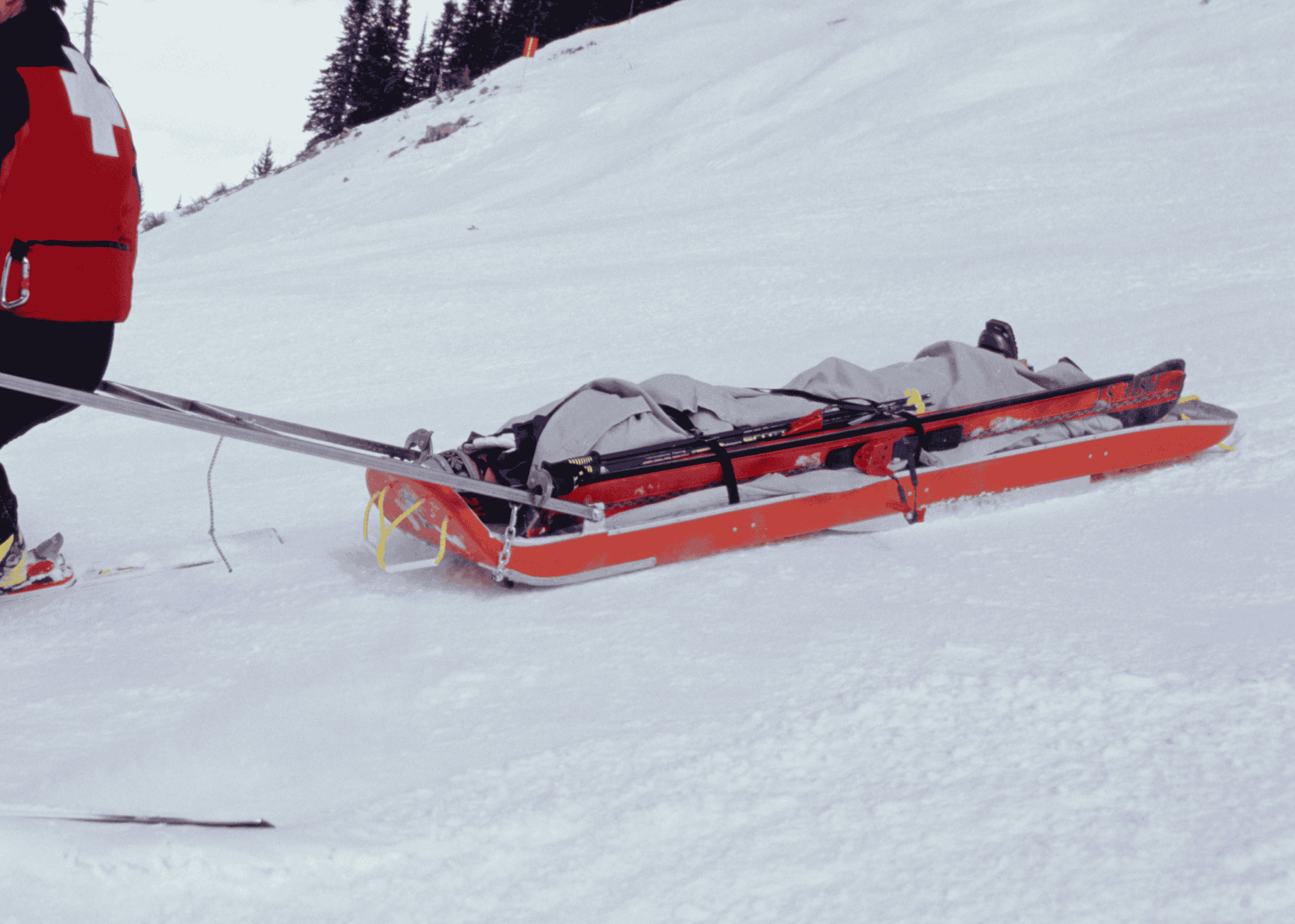 ski patroller taking someone off the hill in a toboggan