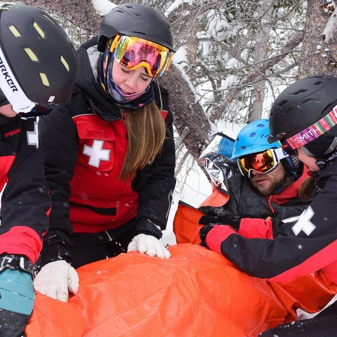 ski patrol helping patient on hill