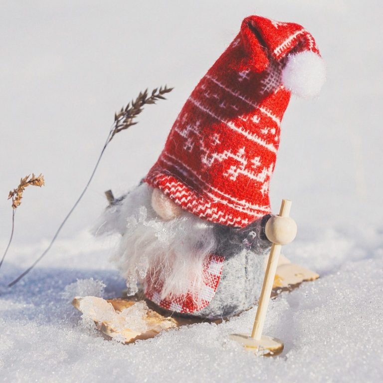 Cute gnome figurine skiing in snowy landscape, adding charm to winter decorations.