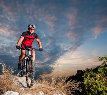 Cyclist on mountain bike races downhill in the nature